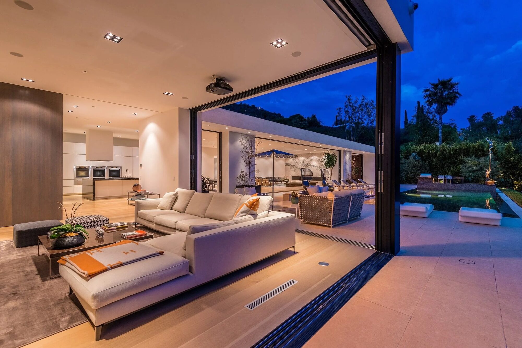 Twilight living room opening onto a pool deck